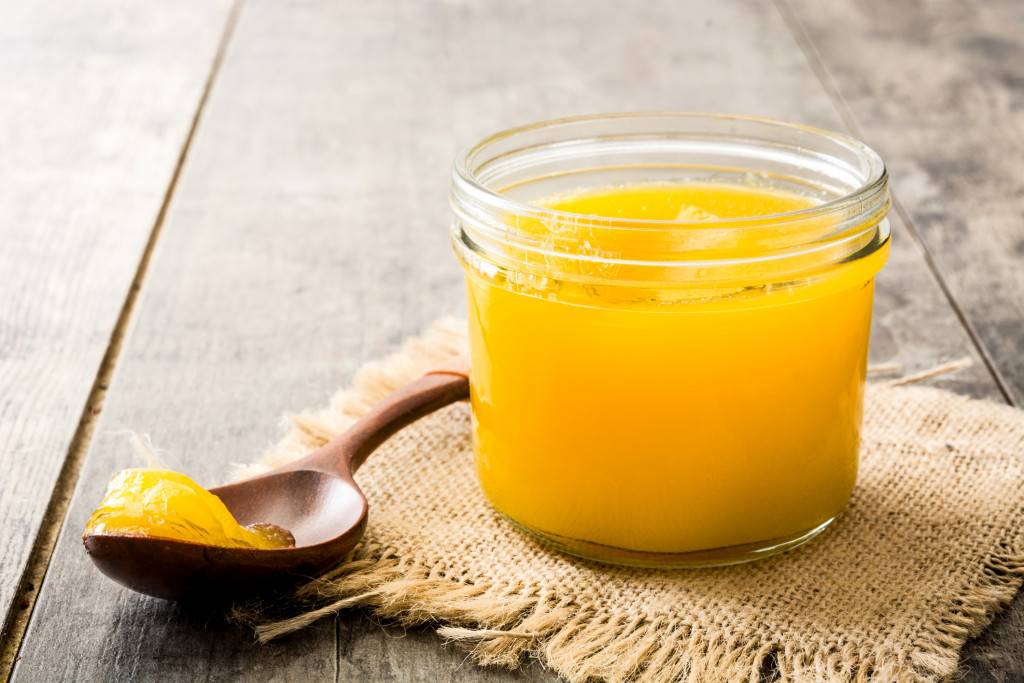 Ghee or clarified butter in jar and wooden spoon on wooden table. |  |